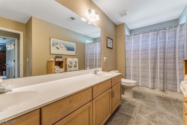bathroom featuring double vanity, toilet, visible vents, and a sink