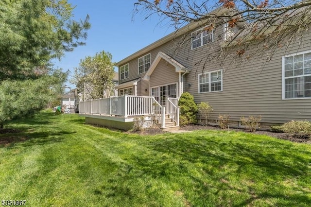 rear view of property featuring a wooden deck and a yard