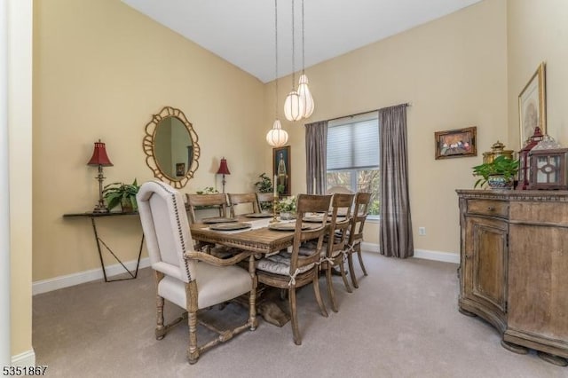 dining room featuring baseboards, light colored carpet, and vaulted ceiling