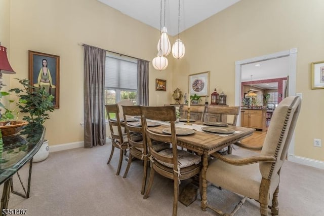 dining room with light colored carpet, baseboards, and a towering ceiling
