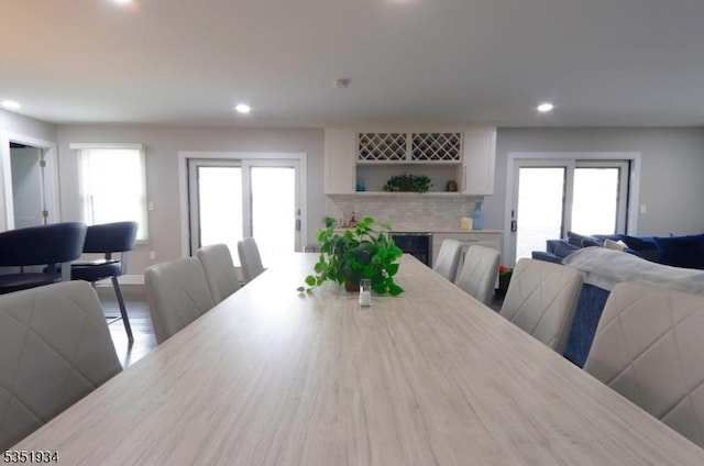dining space featuring a brick fireplace, wood finished floors, baseboards, beverage cooler, and recessed lighting
