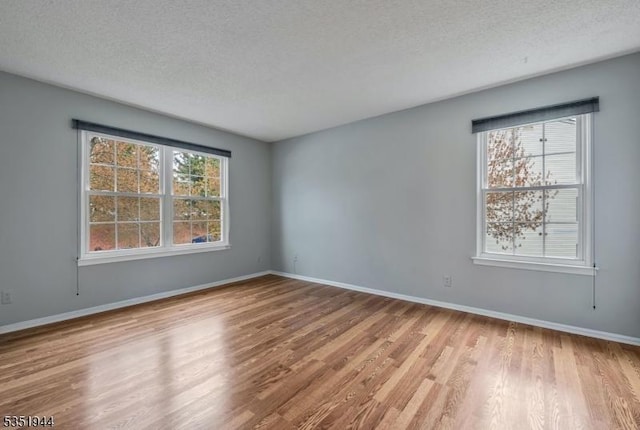 unfurnished room with baseboards, wood finished floors, and a textured ceiling