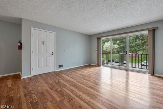 interior space featuring wood finished floors, a textured ceiling, baseboards, and visible vents