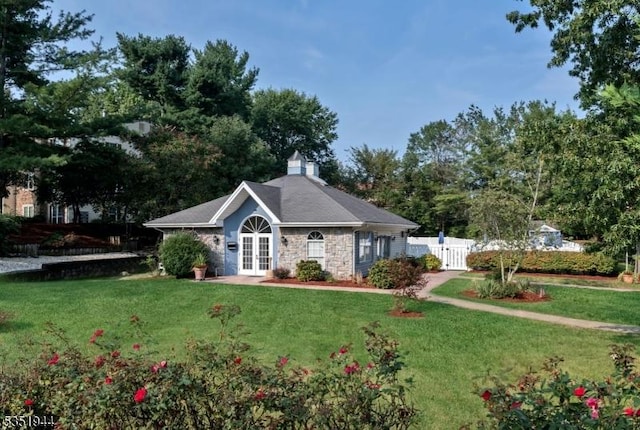 view of front of home featuring french doors, stone siding, a front lawn, and fence