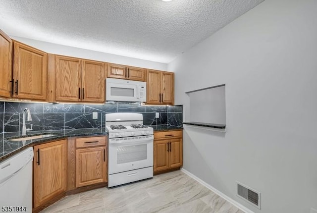 kitchen featuring tasteful backsplash, a sink, a textured ceiling, white appliances, and visible vents