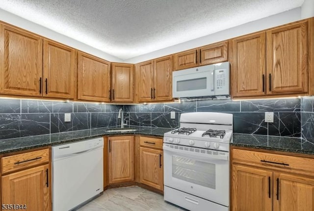 kitchen featuring brown cabinets, marble finish floor, a sink, white appliances, and a textured ceiling