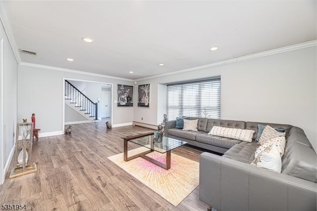 living room with visible vents, crown molding, baseboards, baseboard heating, and stairway