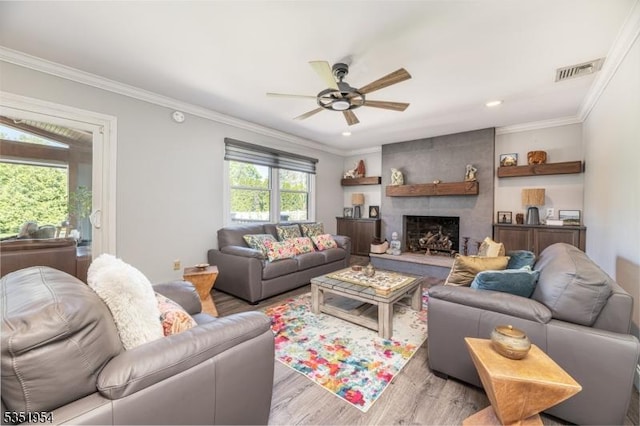 living room with crown molding, ceiling fan, light wood-style flooring, and visible vents