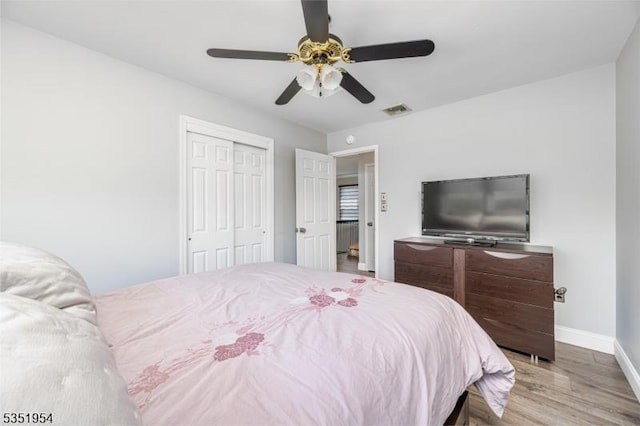 bedroom featuring ceiling fan, baseboards, wood finished floors, visible vents, and a closet
