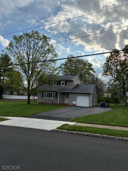 view of front of home with an attached garage, a front lawn, and driveway
