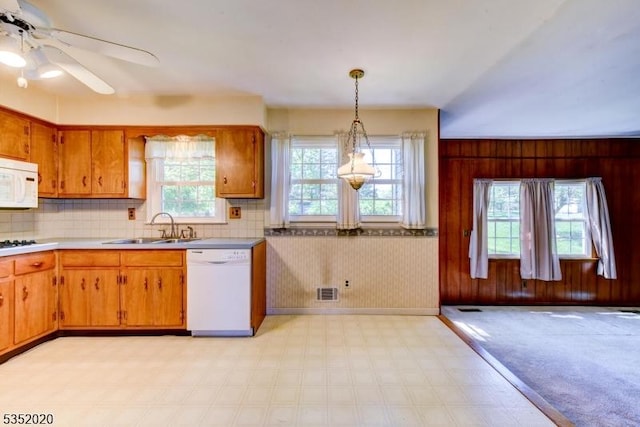 kitchen featuring brown cabinetry, visible vents, a sink, light floors, and white appliances