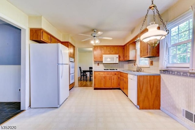 kitchen with white appliances, light countertops, a wainscoted wall, a ceiling fan, and light floors