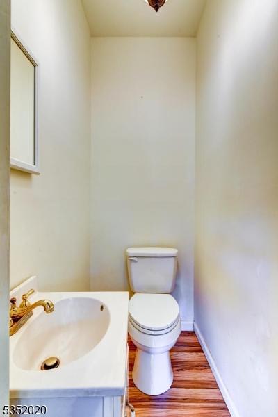 bathroom featuring vanity, baseboards, wood finished floors, and toilet