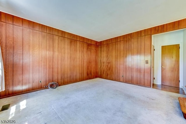 carpeted empty room with wooden walls and visible vents