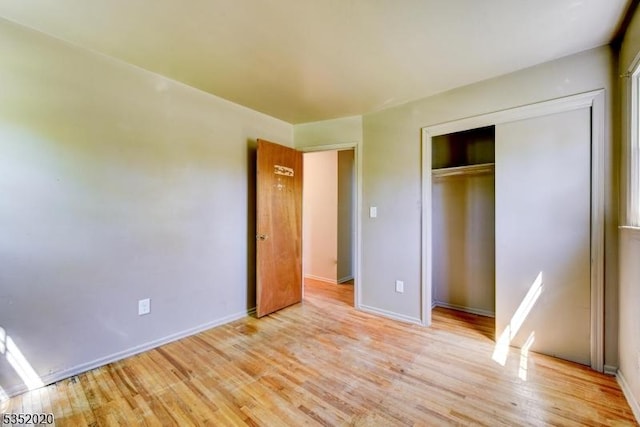 unfurnished bedroom with baseboards, a closet, and light wood-type flooring