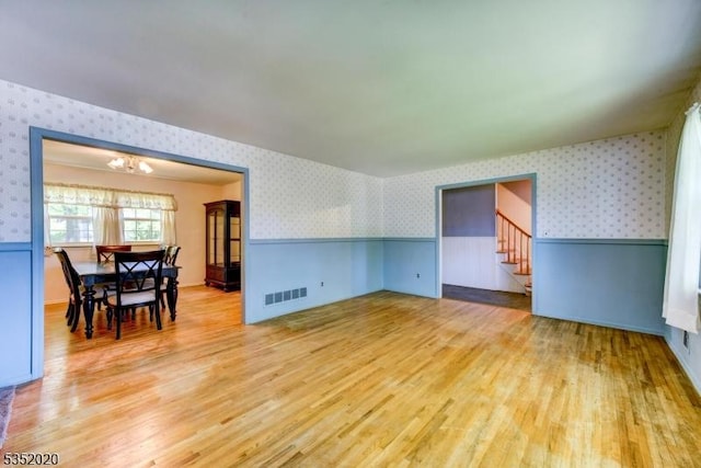 living area featuring wallpapered walls, wainscoting, and light wood finished floors