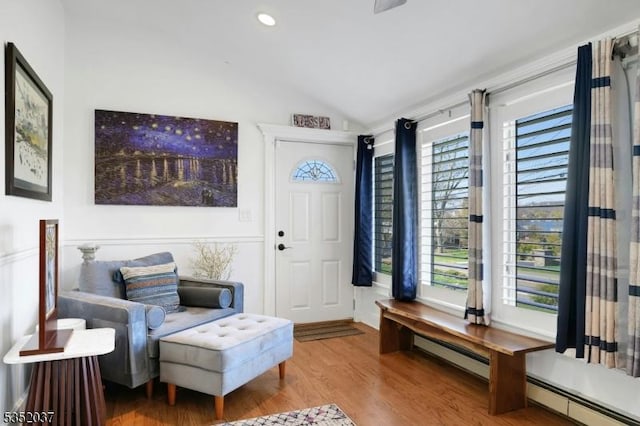 sitting room with a baseboard radiator, wood finished floors, vaulted ceiling, and a healthy amount of sunlight