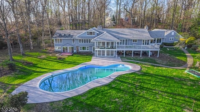rear view of house with a wooden deck, a yard, a patio, and an outdoor pool