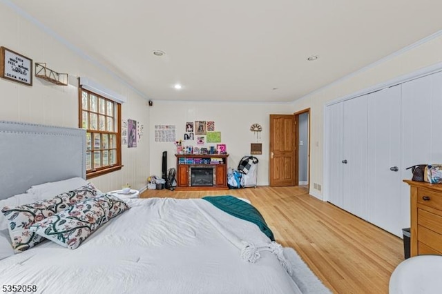 bedroom featuring recessed lighting, ornamental molding, light wood-style floors, and a closet