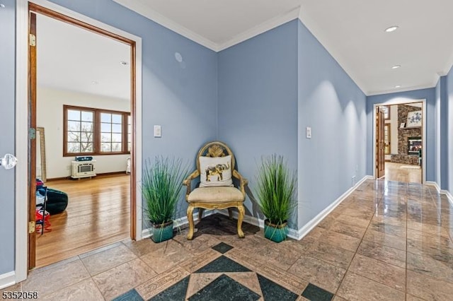 living area featuring baseboards, crown molding, a lit fireplace, and recessed lighting
