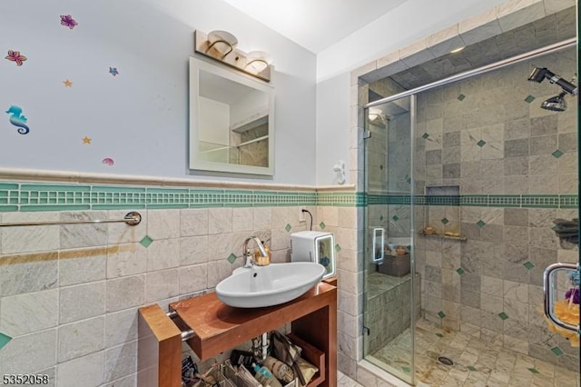 bathroom with tile walls, vanity, wainscoting, and a shower stall