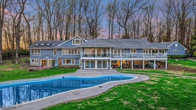 back of property featuring a yard, a patio, an outdoor pool, and a balcony