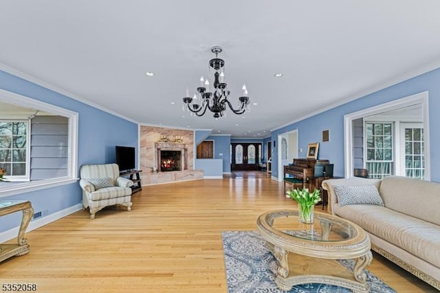 living area featuring wood finished floors, a notable chandelier, baseboards, and ornamental molding