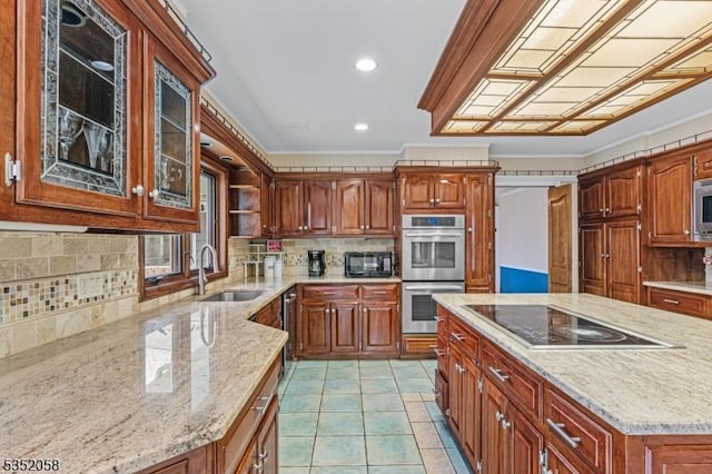 kitchen featuring backsplash, a sink, light stone countertops, black appliances, and glass insert cabinets