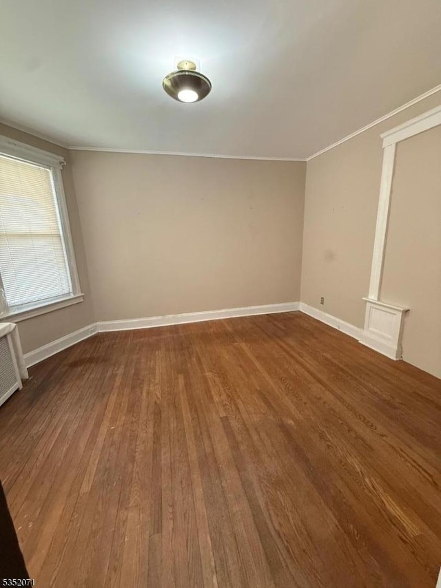 spare room with baseboards, wood finished floors, and ornamental molding