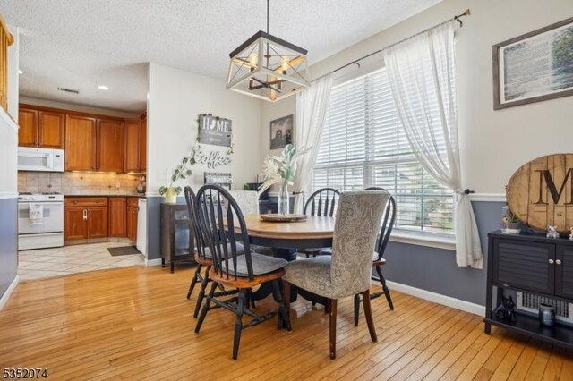 dining room featuring an inviting chandelier, light wood-style floors, baseboards, recessed lighting, and a textured ceiling
