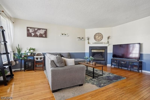 living room featuring a textured ceiling, a glass covered fireplace, and hardwood / wood-style floors