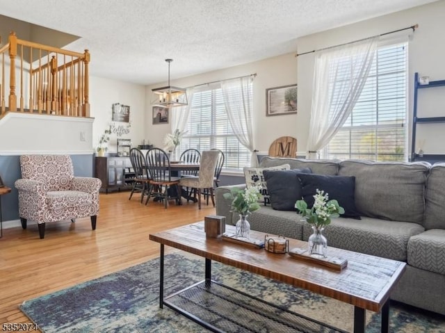 living room with stairs, a textured ceiling, a healthy amount of sunlight, and wood finished floors