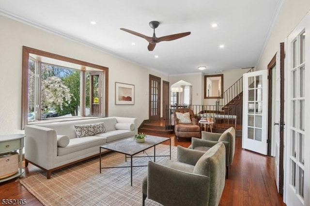 living area featuring stairway, ornamental molding, a ceiling fan, and wood finished floors