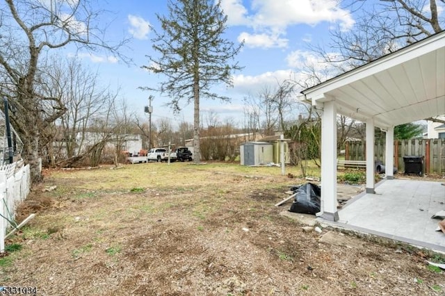 view of yard featuring a storage shed, an outbuilding, a patio, and fence
