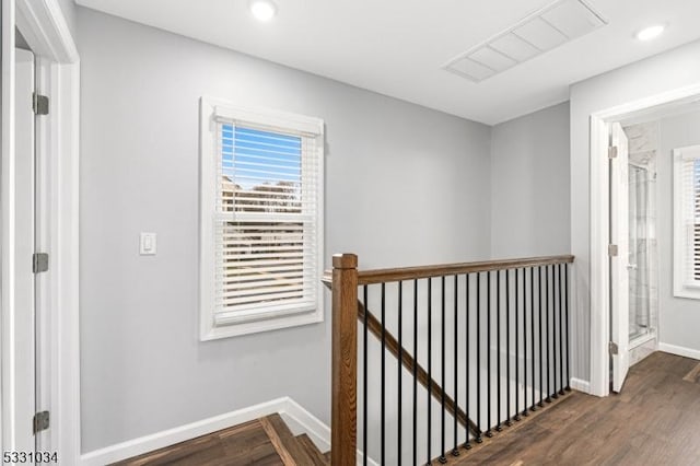 hall featuring baseboards, visible vents, an upstairs landing, and plenty of natural light