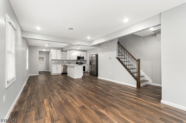 unfurnished living room with baseboards, stairway, and dark wood-style floors