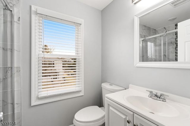 bathroom featuring a shower stall, toilet, vanity, and visible vents