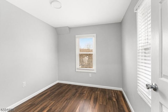 empty room featuring baseboards and dark wood-style floors