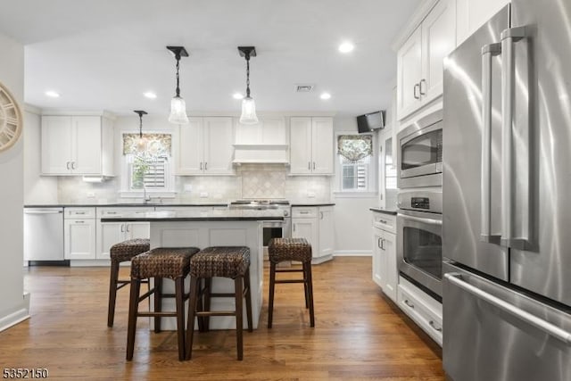 kitchen featuring a breakfast bar area, dark countertops, high end appliances, and decorative backsplash