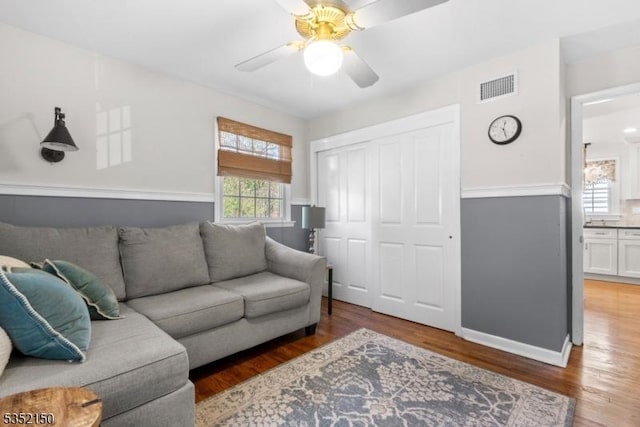 living room with visible vents, baseboards, ceiling fan, and wood finished floors