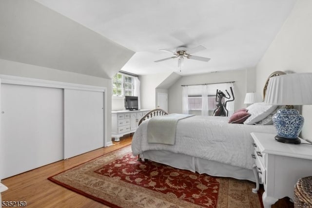 bedroom featuring a closet, light wood-style flooring, ceiling fan, and lofted ceiling