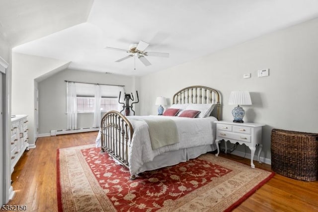 bedroom with a ceiling fan, baseboards, wood finished floors, and a baseboard radiator