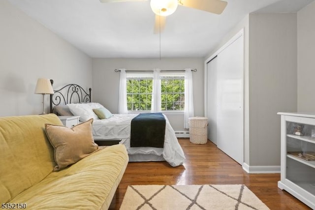 bedroom with a closet, wood finished floors, baseboards, ceiling fan, and baseboard heating