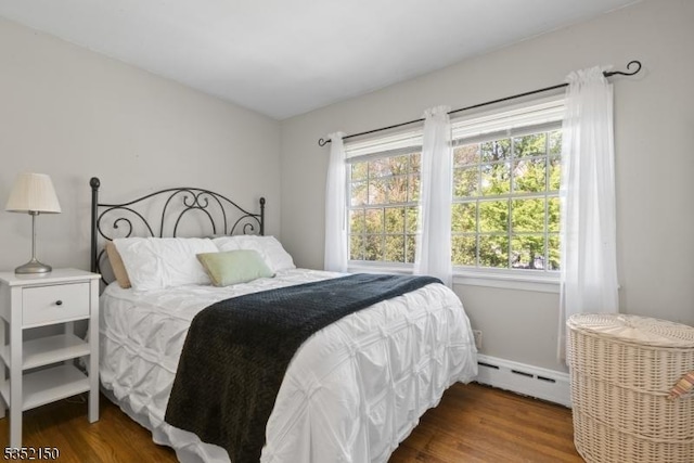 bedroom with a baseboard heating unit and wood finished floors