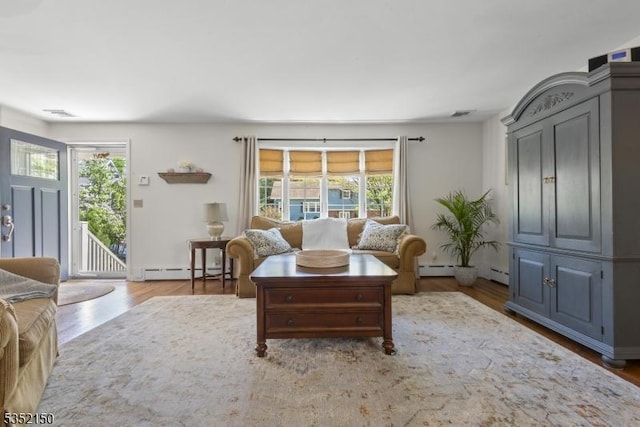 living room featuring wood finished floors, a wealth of natural light, and a baseboard radiator