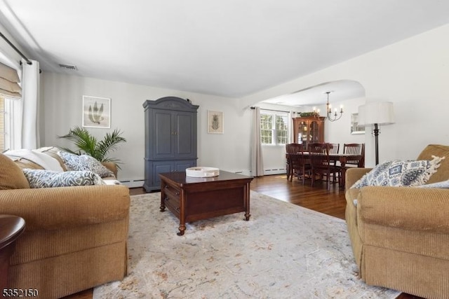 living room with visible vents, baseboard heating, wood finished floors, and a chandelier
