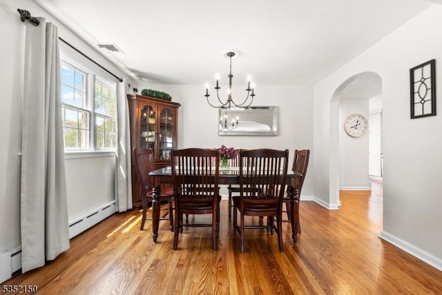 dining space featuring arched walkways, a chandelier, baseboards, wood finished floors, and visible vents