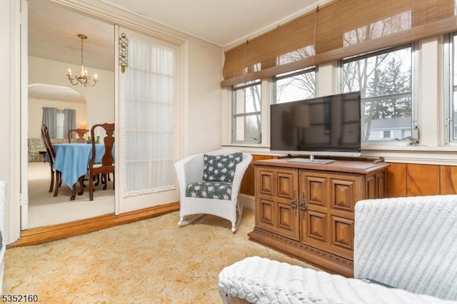 sitting room featuring arched walkways, crown molding, light colored carpet, and a notable chandelier