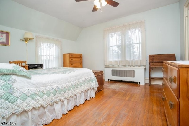 bedroom featuring hardwood / wood-style floors, vaulted ceiling, ceiling fan, and radiator