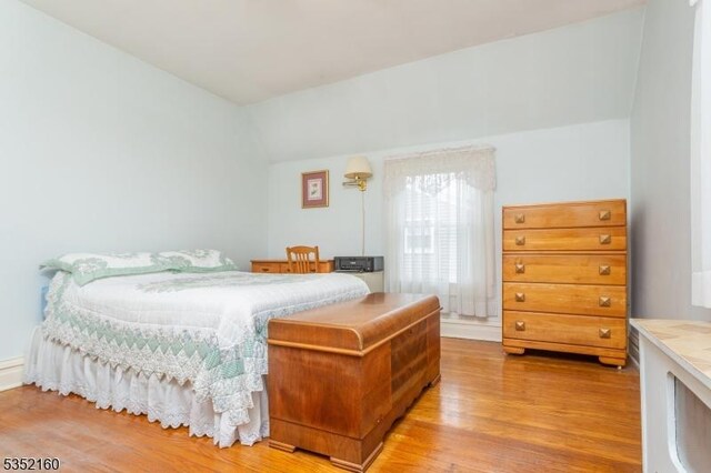 bedroom with vaulted ceiling and wood finished floors